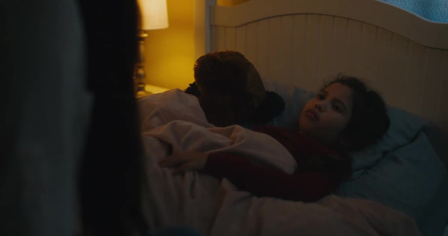 A mother putting her daughter to bed