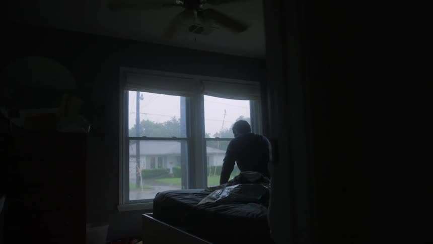 Man looks out bedroom windows