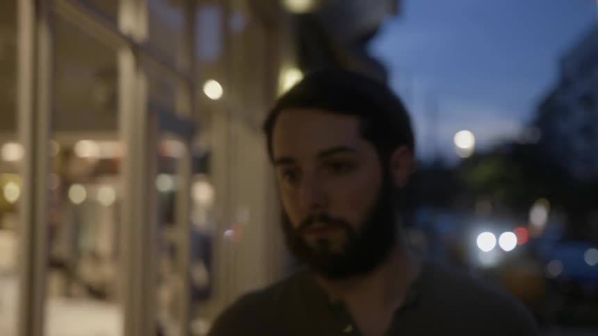 Man walks down a city sidewalk at night