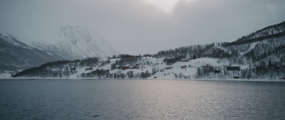 Ripples move across a lake next to a snowy mountain range