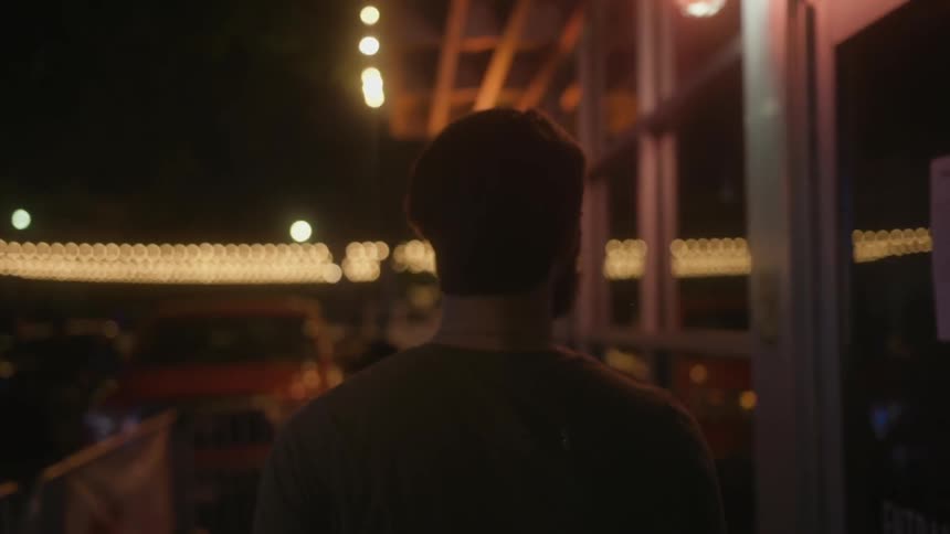 A man is walking past a building at night