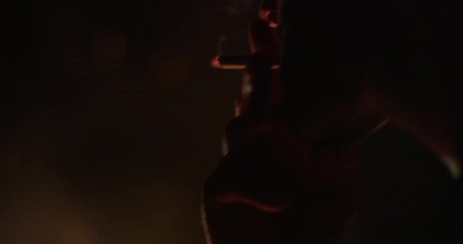 A person is smoking a cigarette by a campfire at night