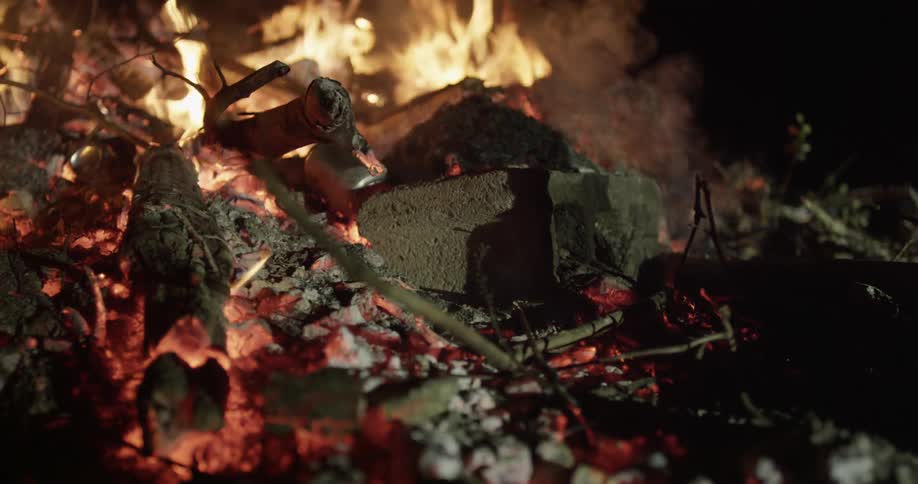 A fire burns outside at night