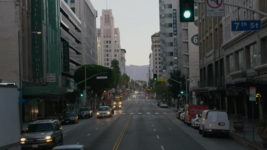 Vehicle drives down the street in the city with skyscrapers at sunset
