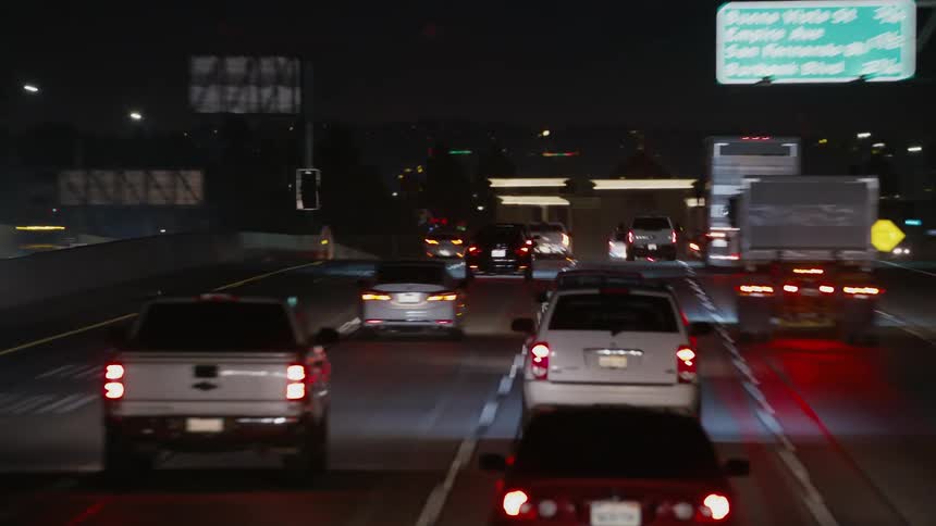 Tail lights and headlights shine as traffic moves on a busy highway at night