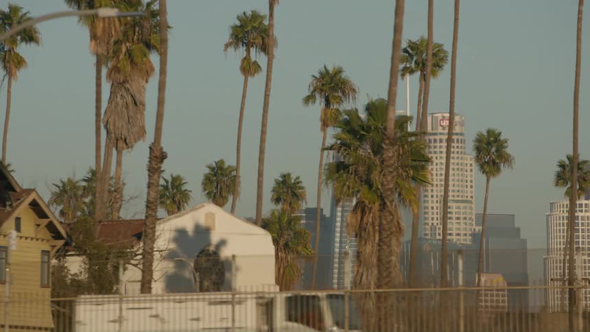 Vehicles pass by domed building and nearby house on foggy day with skyscrapers in the background