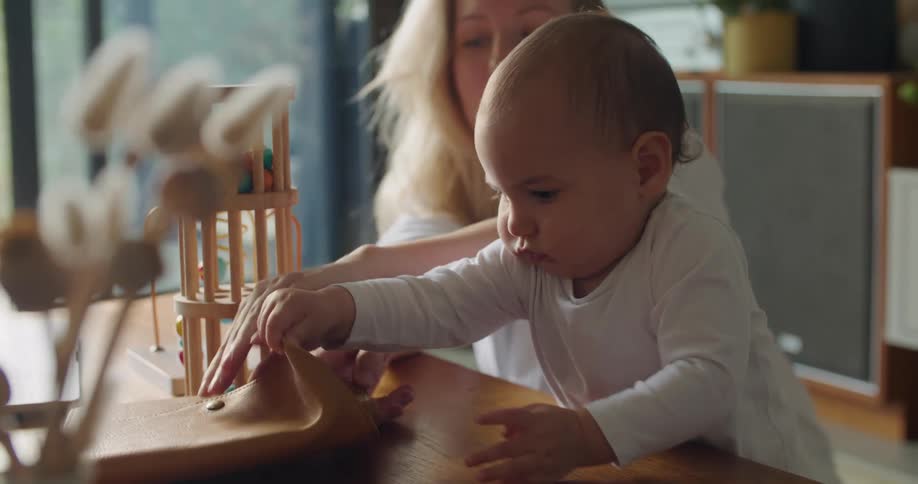 Mother helps her baby open a notebook bound on leather at home