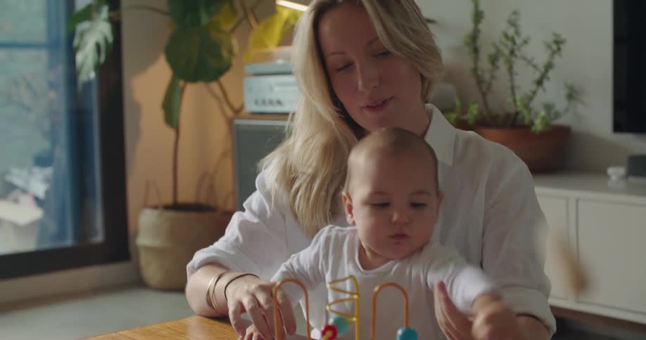 Blonde mother with white shirt parents baby in living room at home