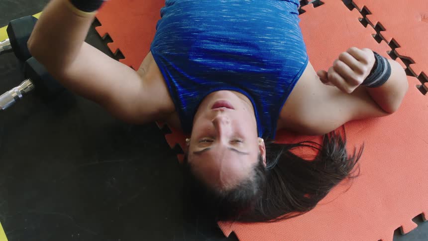 A woman stretches her arms while lying down on foam gym squares