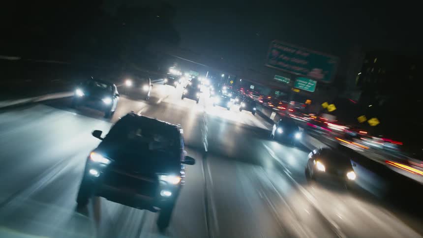 Headlights shine brightly on vehicles traveling on a highway at night