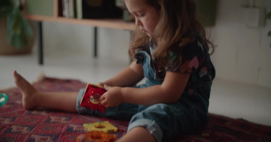 A little girl sits on a bed at home and plays