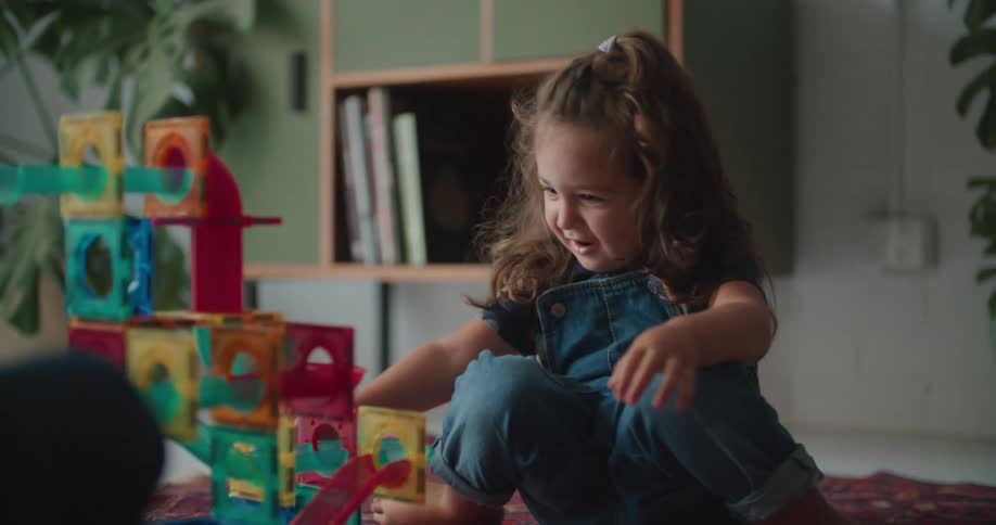 A man is sitting on the floor with a little girl playing with toys and building blocks