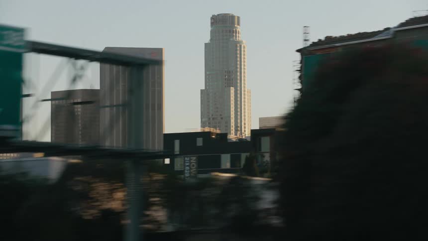 Freeway passes graffiti decorated buildings with skyscrapers in the background