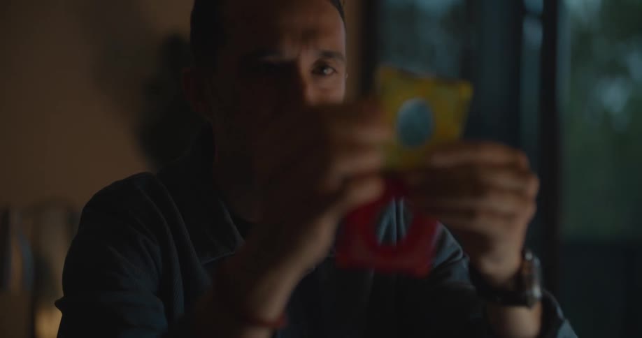 A man is holding square objects in his hands and looking at them