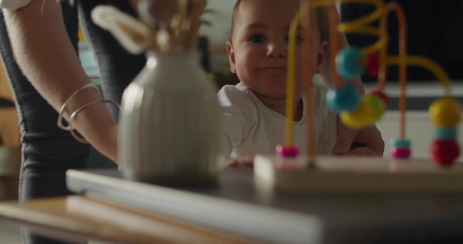 A woman helps a crawling baby as he attempts to stand