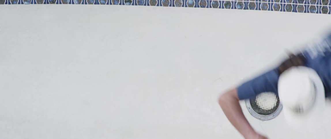 A skateboarder rides up the side of an empty pool