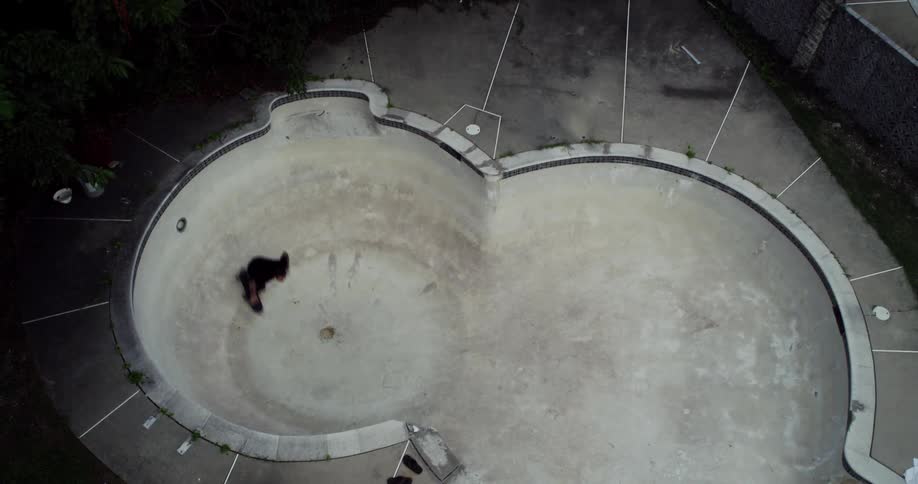 A man skateboarding in an empty pool