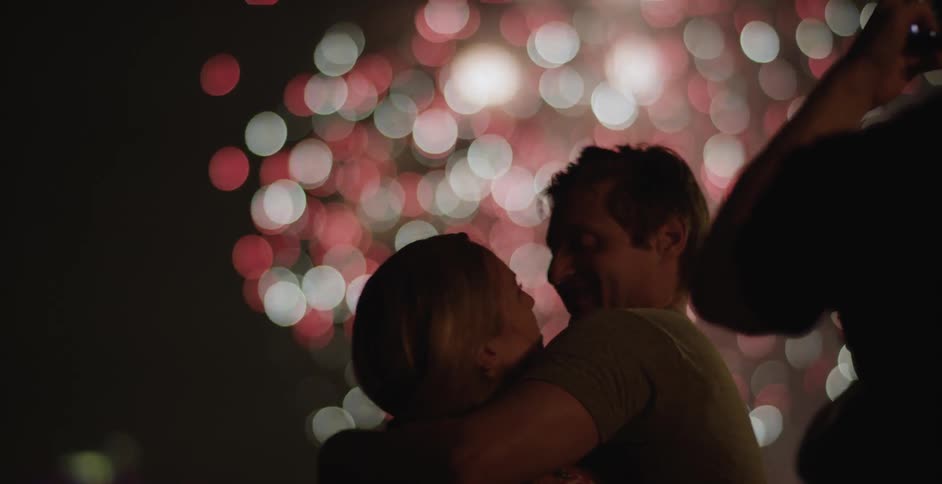 A couple kissing as fireworks explode in the background
