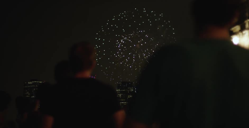 People stand outside at night watching fireworks