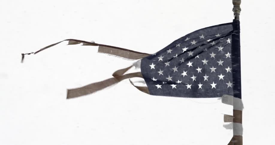A torn american flag blows as it snows