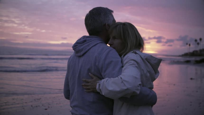 Man and woman dance on a beach at sunset