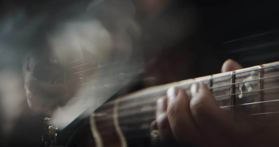 Close up of mans hands playing guitar with plectrum