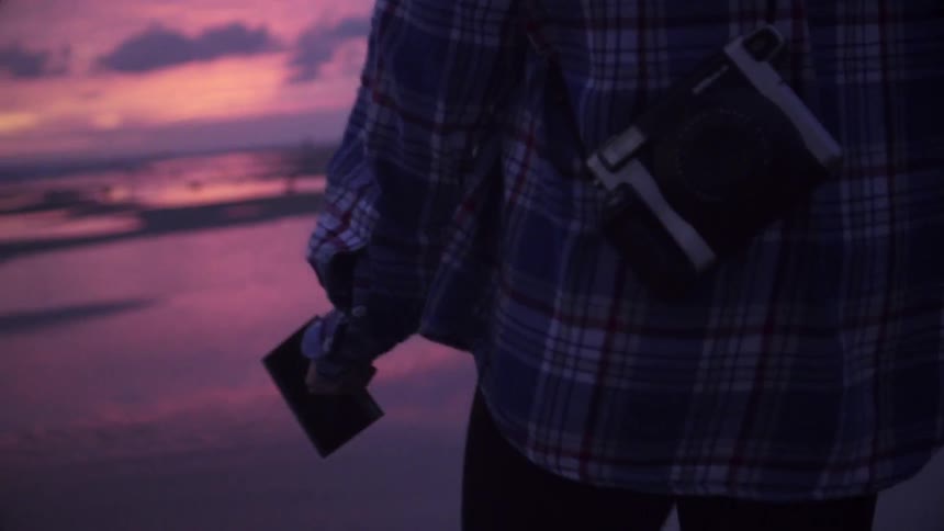 A person is holding something as they walk on the beach