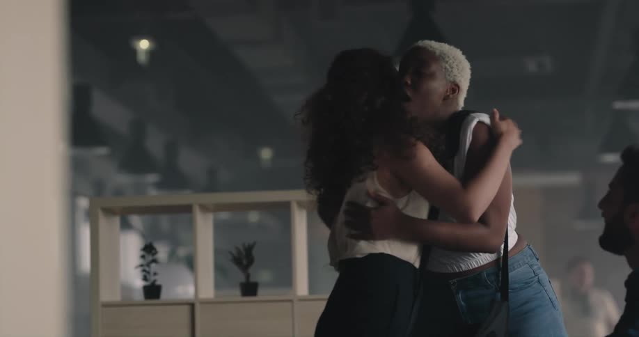 Happy woman greets her coworkers with hugs in the office at morning