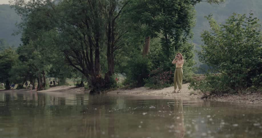 A woman is taking photos by the water
