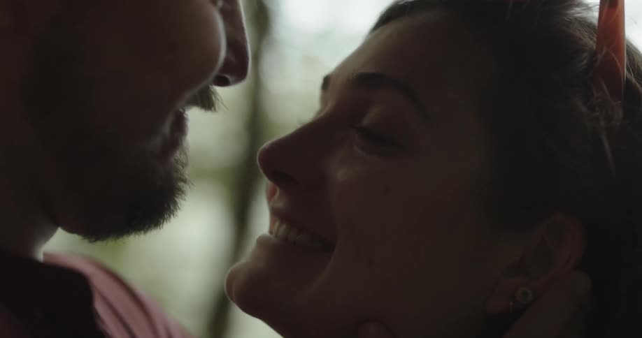 Man caressing the face of his girlfriend and romantically talking to her and kissing her forehead