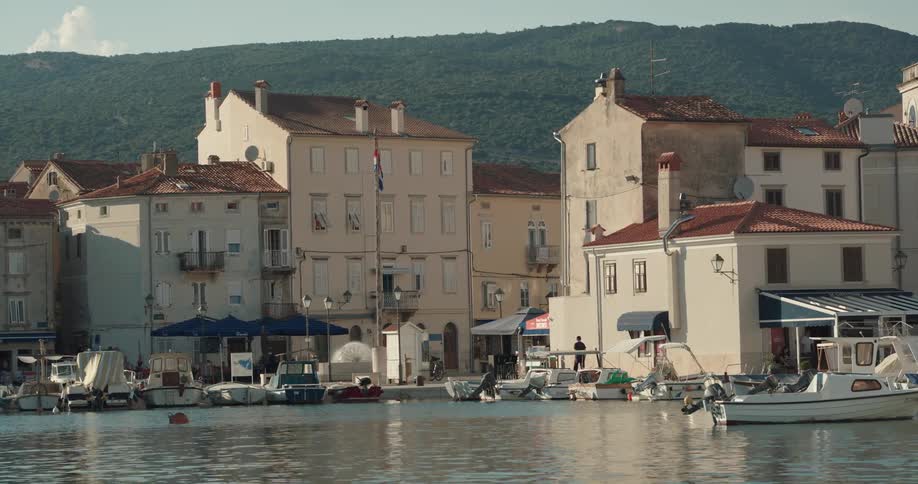 Boats floating on a pier in a small coastal town at evening