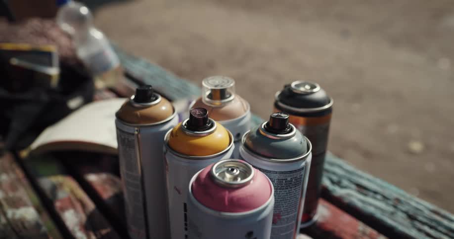 A person quickly sets down one spray paint can in order to pick up one of another color