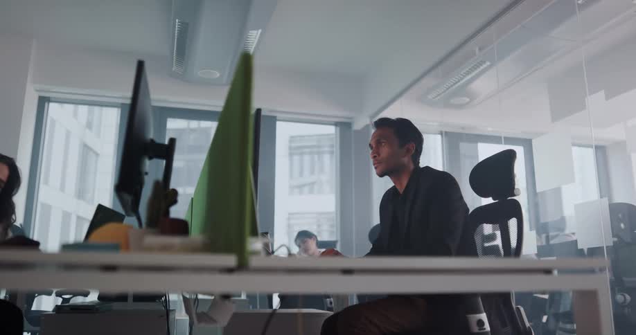 Man looks at a monitor then types on a keyboard in an office
