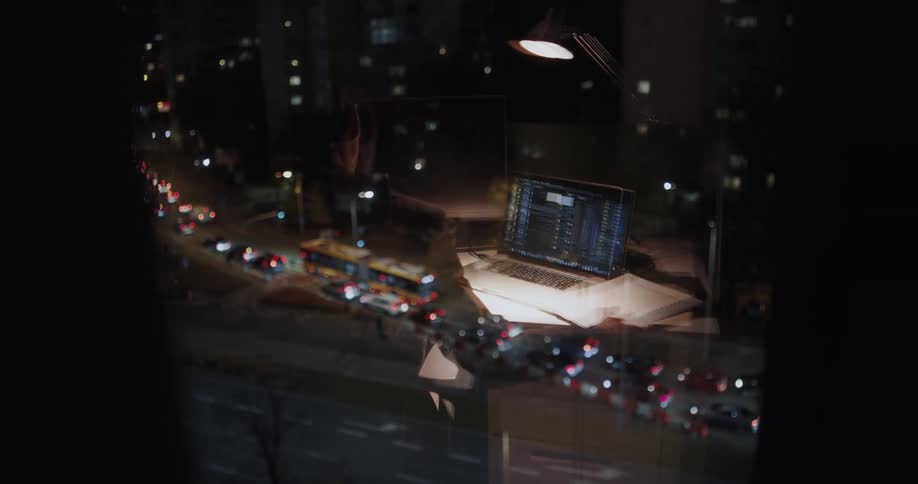 A man works late in the office as traffic below passes by his building