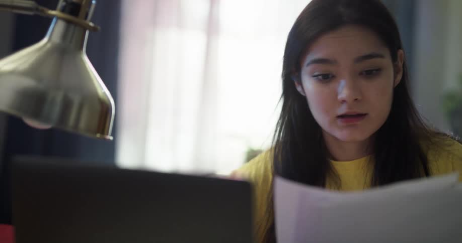 A college student discusses classwork during a video call on her laptop