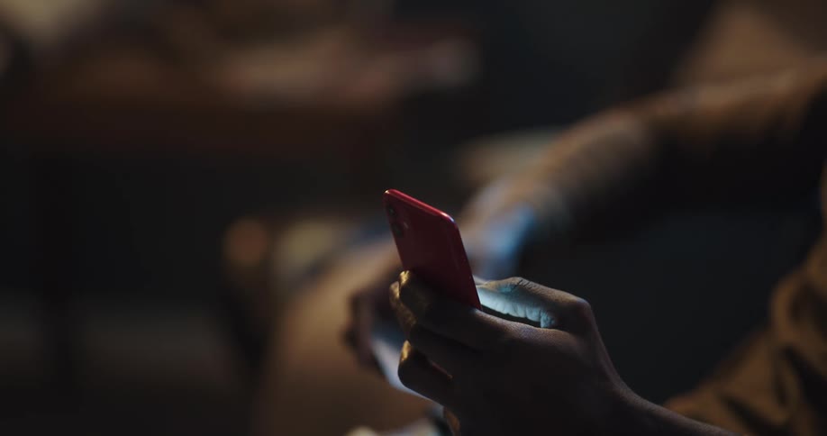 Man enters payment information into smartphone while sitting in living room