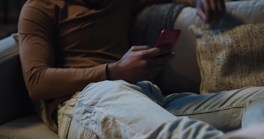 Black man sitting on the couch using his smartphone