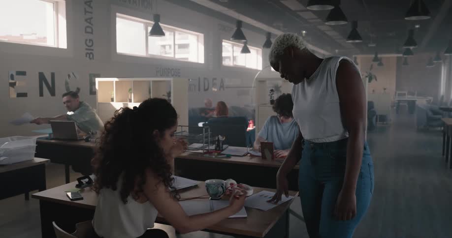 Supervisor walks around the office talking to employees working at desks
