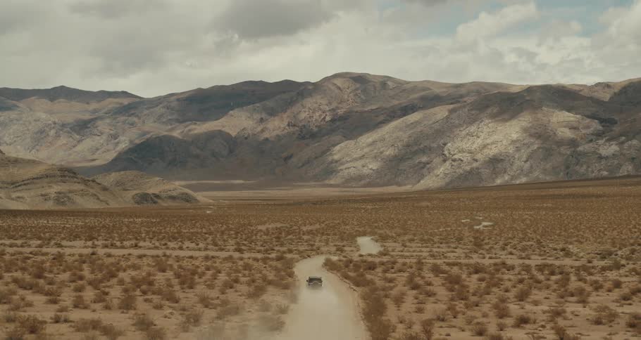 A vehicle drives through the desert