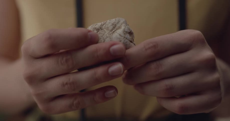 Close up of a woman turning a small white rock on her hands