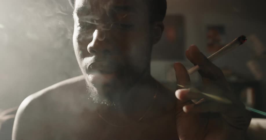 A man smokes a marijuana joint on his couch