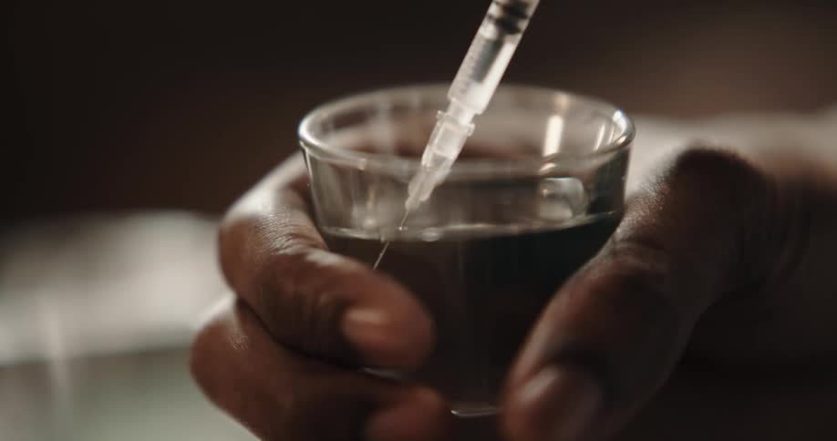 A black man fills a syringe with a drug