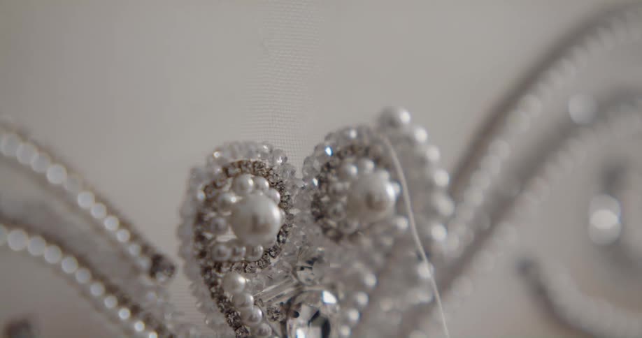 Fashion designer sewing white pearls and sequins over a white lace cloth