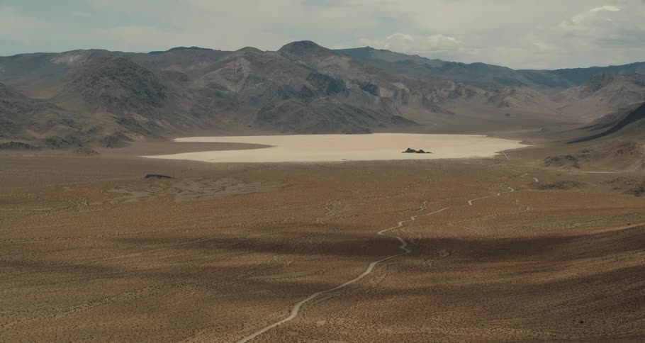 Aerial view of dirt road in the desert with mountain range