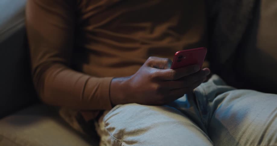 Black man sitting on the couch using his smartphone