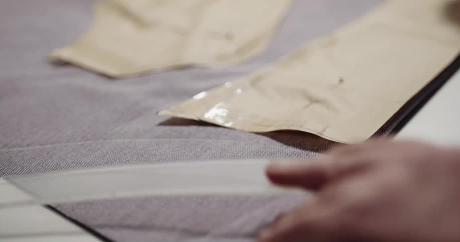Person marks fabric with a piece of chalk moving pattern pieces pinned to fabric surface
