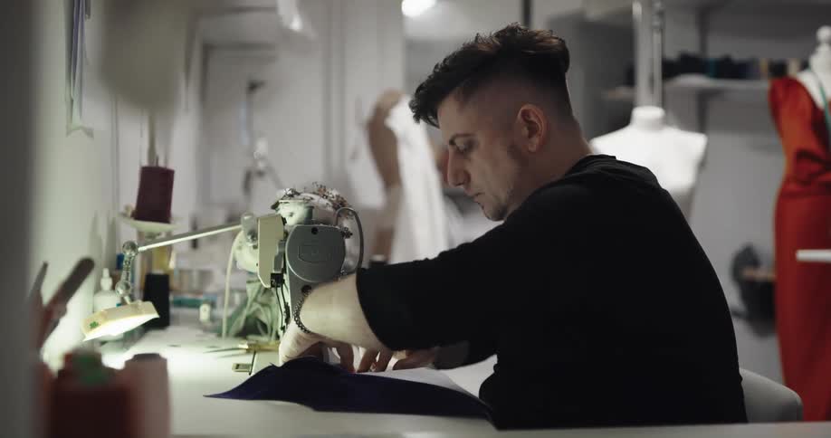 A man pins fabric together before running it through a sewing machine