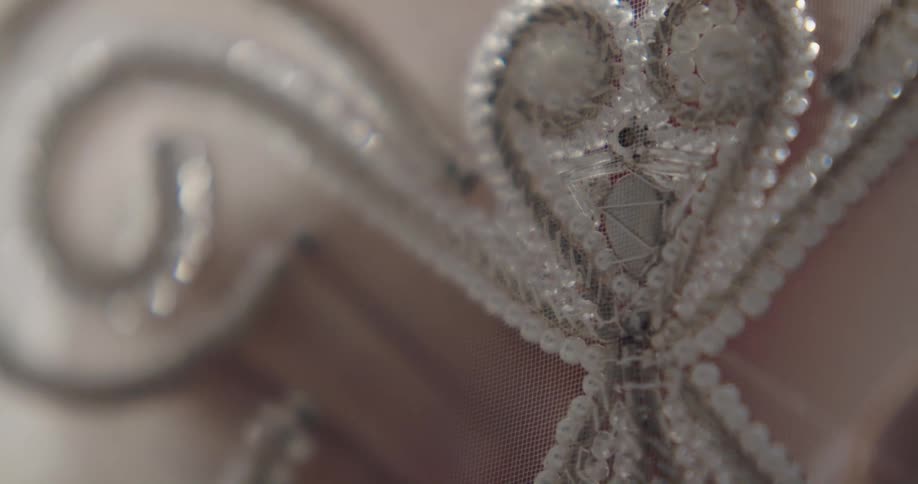 Fashion designer sewing silver sequins over a lace cloth