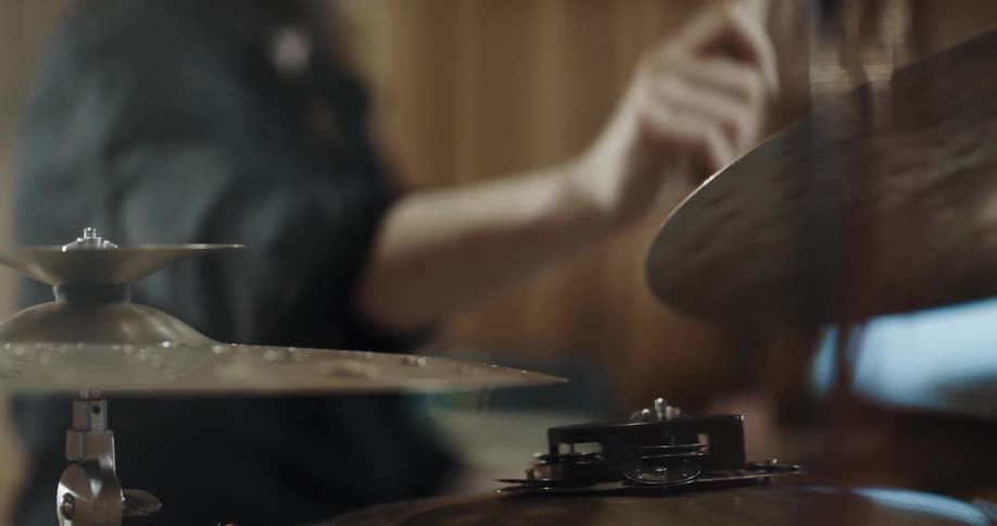Man holds a drumstick in each hand and uses them to tap the cymbals in front of him