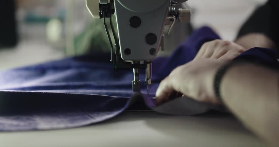 A man is using a sewing machine indoors